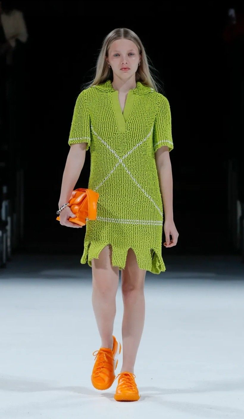 Model wearing Bottega Veneta green dress with orange shoes & bag on the runway